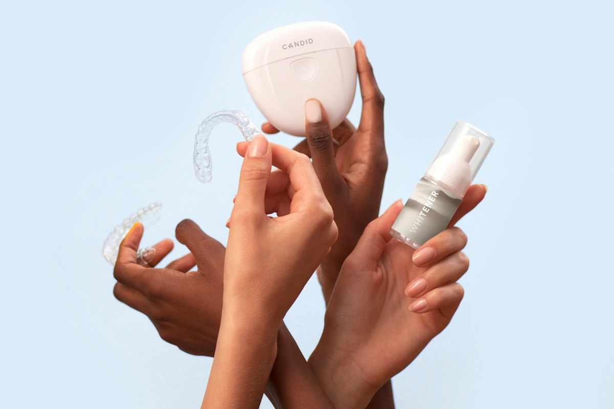 Hands holding clear dental aligners next to a storage case