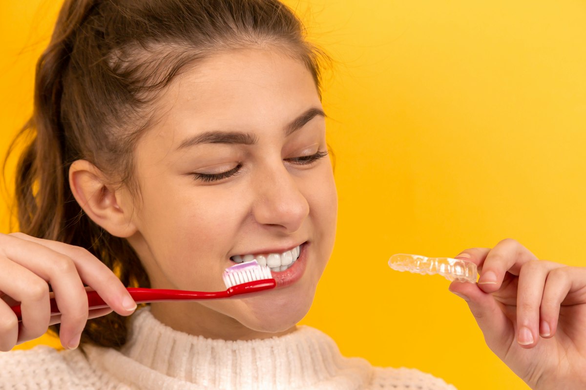 Smiling girl brushing her teeth with a red toothbrush
